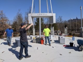 A worker guides a portion of the monument as it hangs from a crane